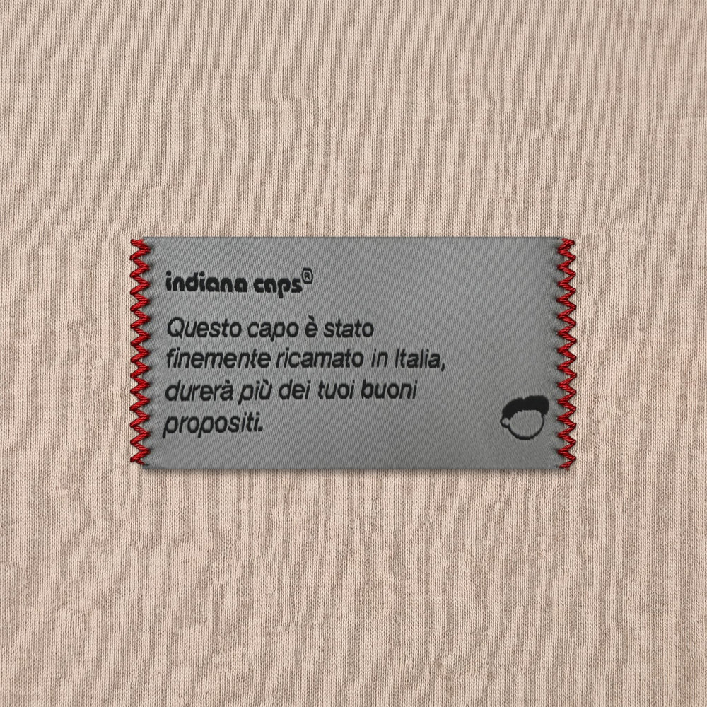 Dettaglio etichetta Indianacaps cuciture rosse su beige